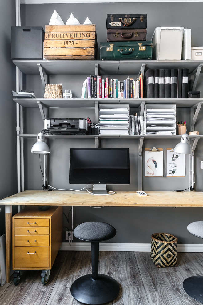 Ejemplo de despacho nórdico pequeño sin chimenea con paredes grises, suelo de madera en tonos medios, escritorio independiente y suelo gris