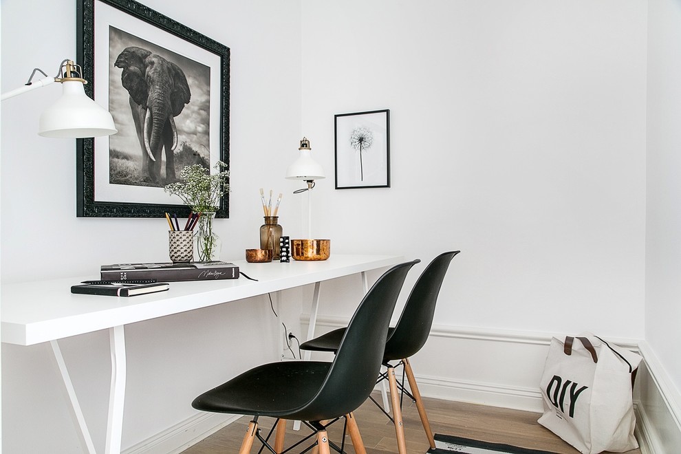 Imagen de despacho nórdico de tamaño medio sin chimenea con paredes blancas, suelo de madera clara y escritorio independiente