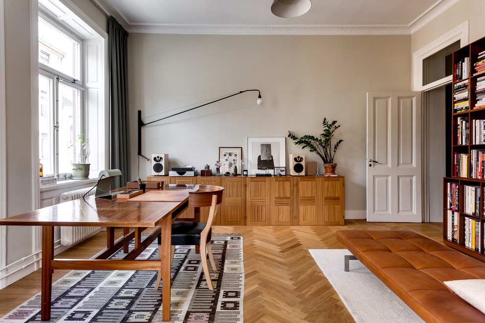 Large scandinavian study in Stockholm with grey walls, light hardwood flooring, a freestanding desk and no fireplace.