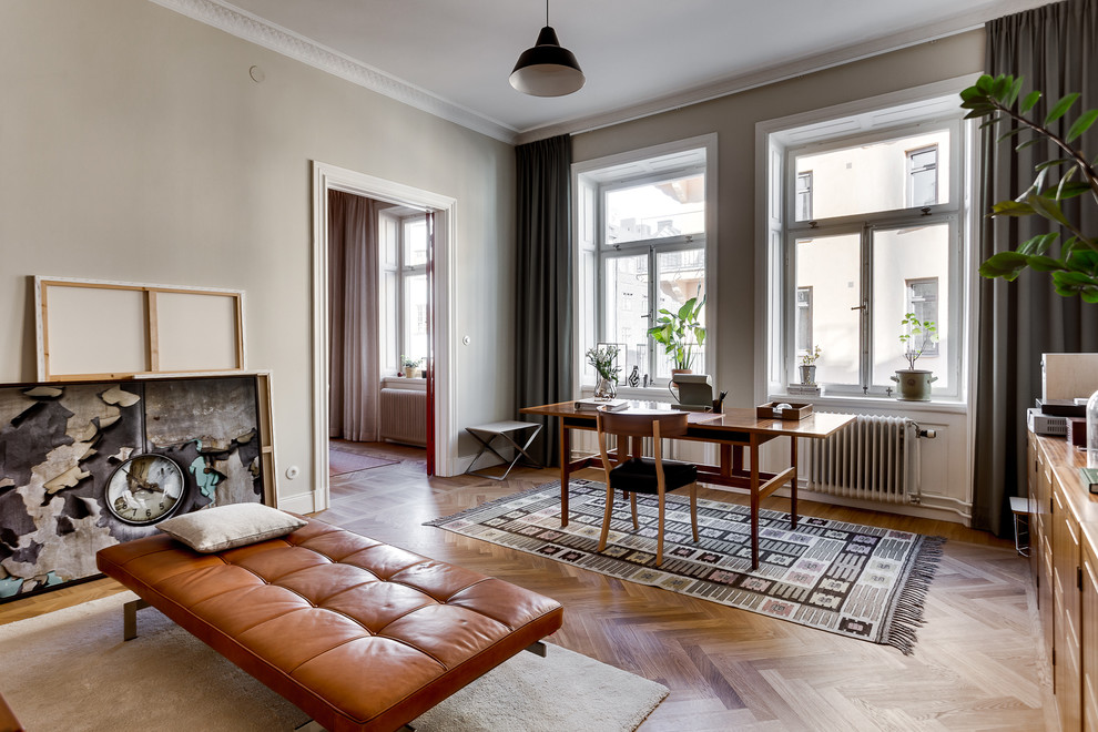 Mittelgroßes Nordisches Arbeitszimmer mit Arbeitsplatz, grauer Wandfarbe, braunem Holzboden und freistehendem Schreibtisch in Stockholm