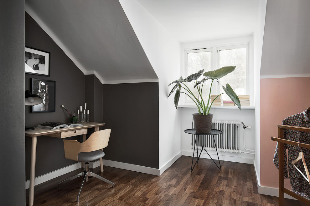 Mittelgroßes Skandinavisches Arbeitszimmer ohne Kamin mit weißer Wandfarbe, dunklem Holzboden und freistehendem Schreibtisch in Stockholm