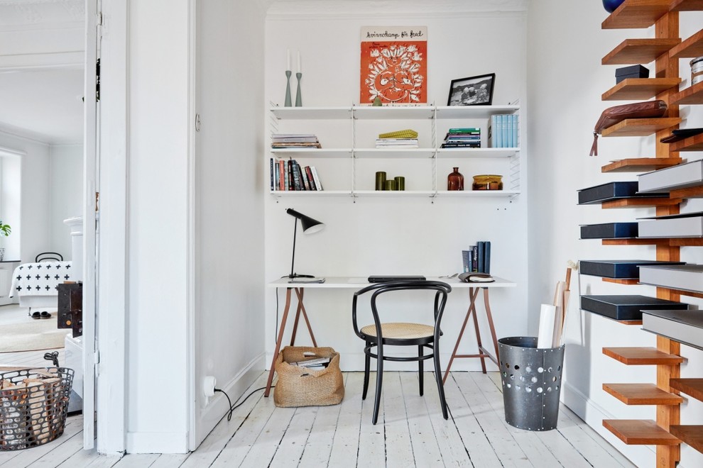 Idéer för mellanstora minimalistiska hemmabibliotek, med vita väggar, målat trägolv och ett fristående skrivbord