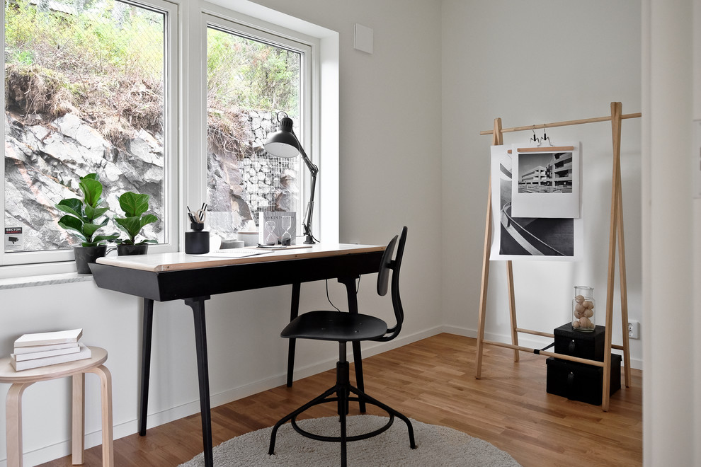 ストックホルムにある北欧スタイルのおしゃれなホームオフィス・書斎 (白い壁、無垢フローリング、自立型机、白い床) の写真