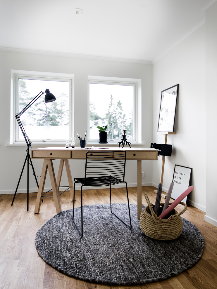 Exempel på ett skandinaviskt arbetsrum, med vita väggar, mellanmörkt trägolv, ett fristående skrivbord och brunt golv
