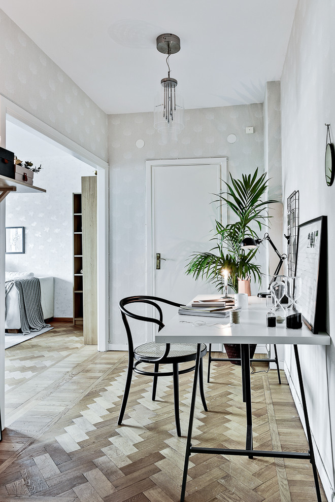 Mittelgroßes Nordisches Arbeitszimmer mit weißer Wandfarbe, braunem Holzboden und freistehendem Schreibtisch in Stockholm