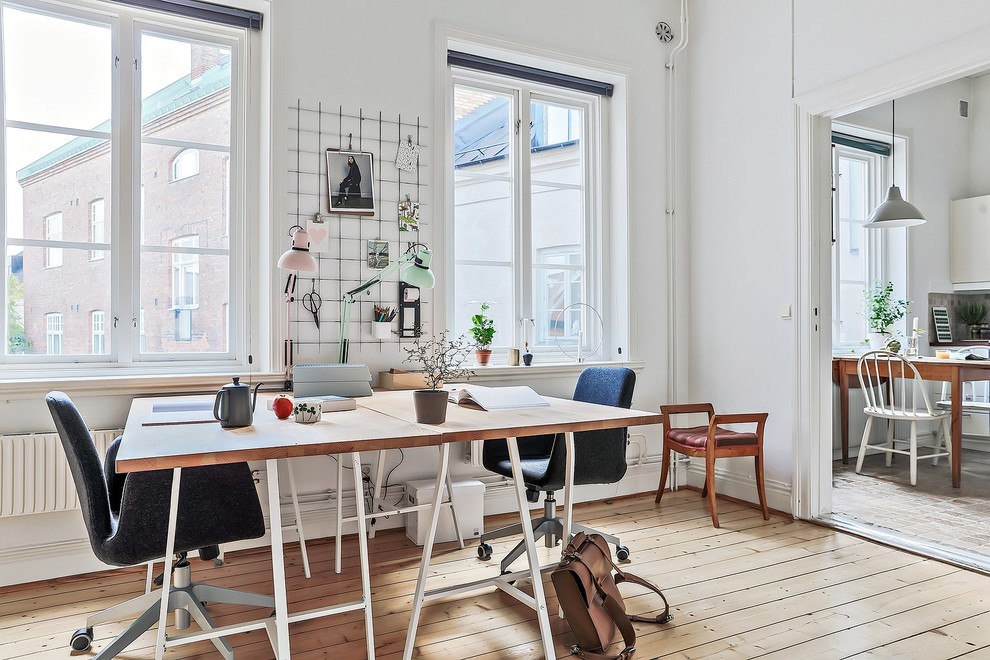 Idéer för minimalistiska hemmabibliotek, med vita väggar, ljust trägolv och ett fristående skrivbord