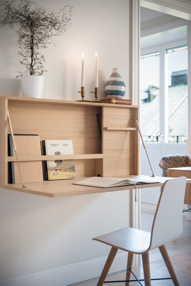 Diseño de despacho escandinavo grande sin chimenea con paredes grises, suelo de madera en tonos medios y escritorio empotrado
