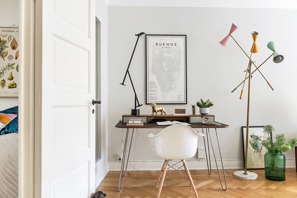 This is an example of a medium sized scandi study in Stockholm with grey walls, light hardwood flooring, a freestanding desk and no fireplace.