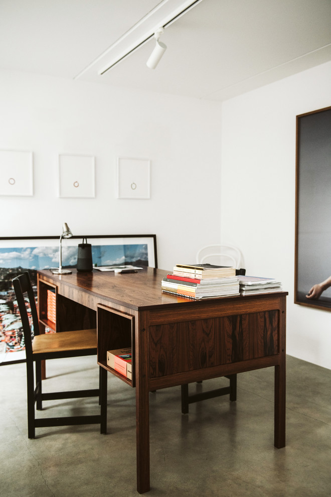 Modelo de despacho nórdico con paredes blancas, suelo de cemento, escritorio independiente y suelo gris