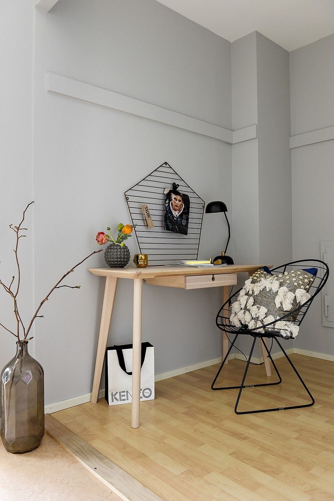 Inredning av ett minimalistiskt mellanstort arbetsrum, med grå väggar, ljust trägolv, ett fristående skrivbord och gult golv