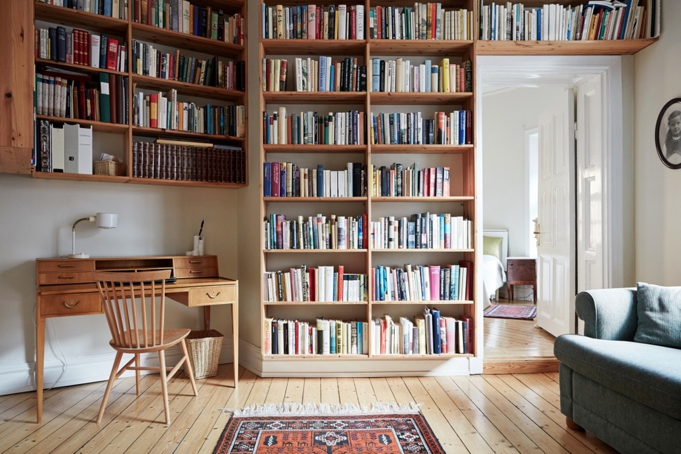 Idéer för stora vintage hemmabibliotek, med vita väggar, ljust trägolv och ett fristående skrivbord
