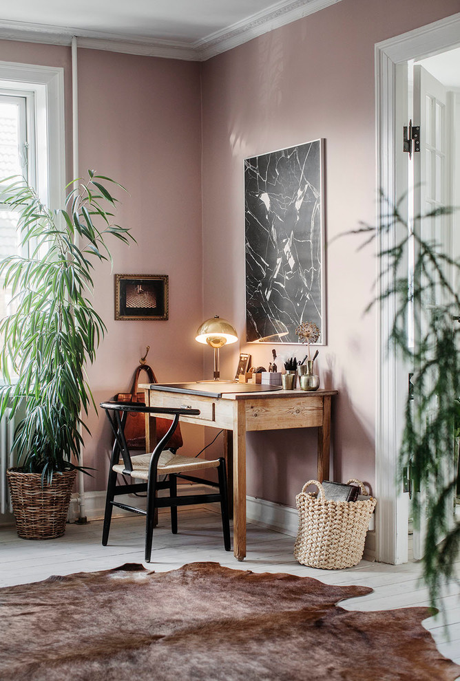 Bild på ett mellanstort skandinaviskt arbetsrum, med lila väggar, målat trägolv och ett fristående skrivbord