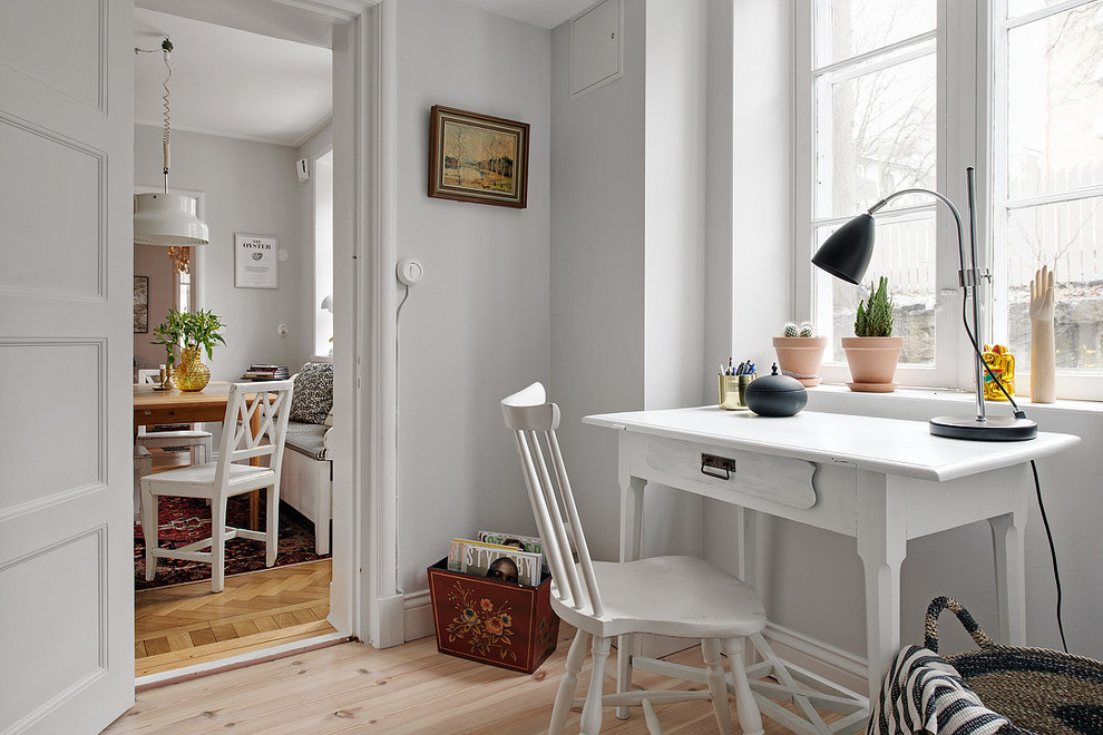 Bild på ett mellanstort skandinaviskt hemmabibliotek, med grå väggar, ljust trägolv och ett fristående skrivbord