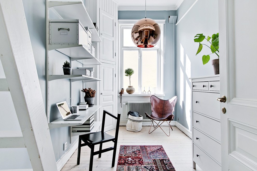 Kleines Skandinavisches Arbeitszimmer mit blauer Wandfarbe, hellem Holzboden, beigem Boden, Arbeitsplatz und Einbau-Schreibtisch in Sonstige