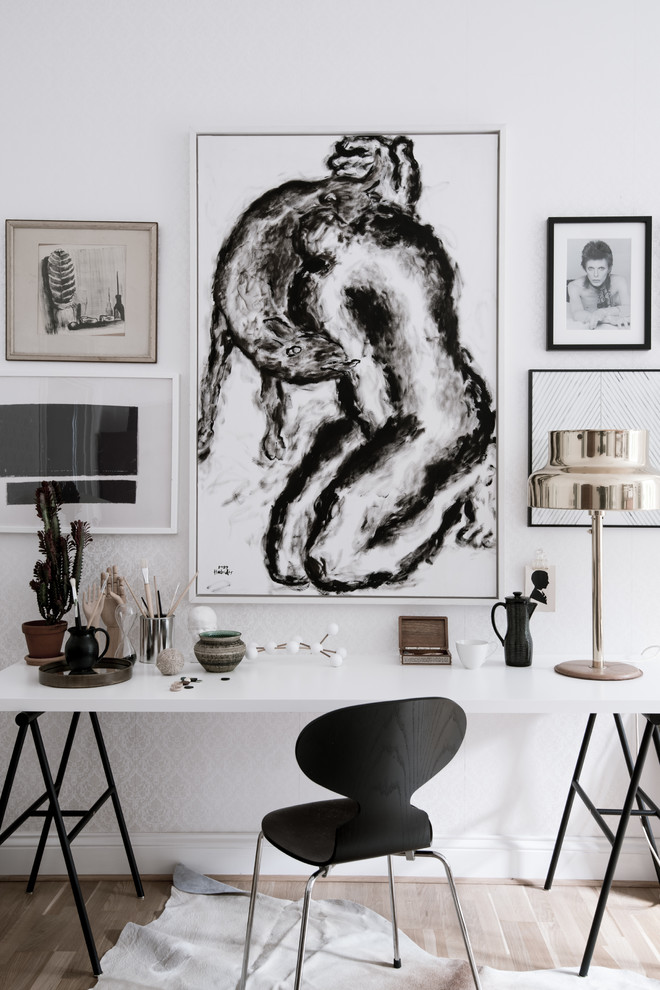 Inredning av ett minimalistiskt stort hobbyrum, med vita väggar, ljust trägolv och ett fristående skrivbord