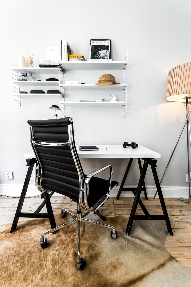На фото: кабинет в скандинавском стиле с белыми стенами, светлым паркетным полом, отдельно стоящим рабочим столом и бежевым полом без камина с