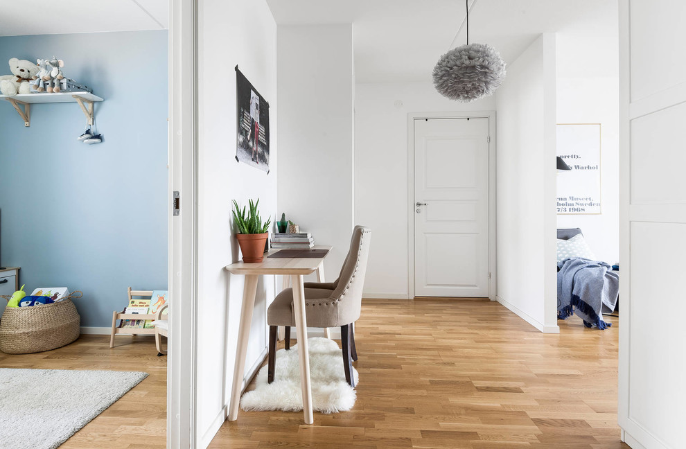 Foto på ett skandinaviskt arbetsrum, med mellanmörkt trägolv, ett fristående skrivbord och brunt golv