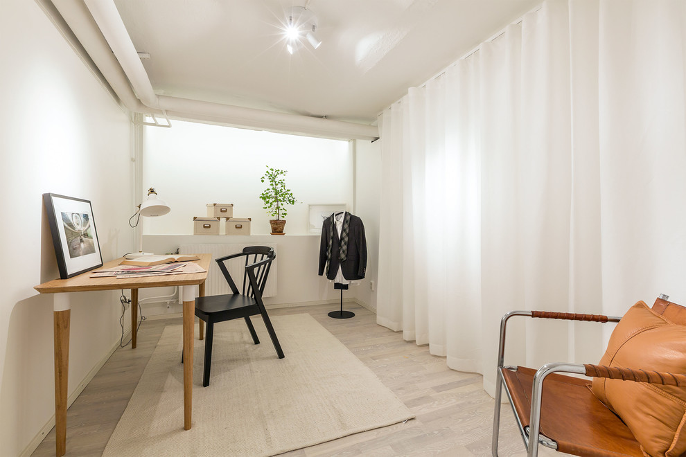 Mittelgroßes Skandinavisches Arbeitszimmer ohne Kamin mit weißer Wandfarbe und hellem Holzboden in Stockholm