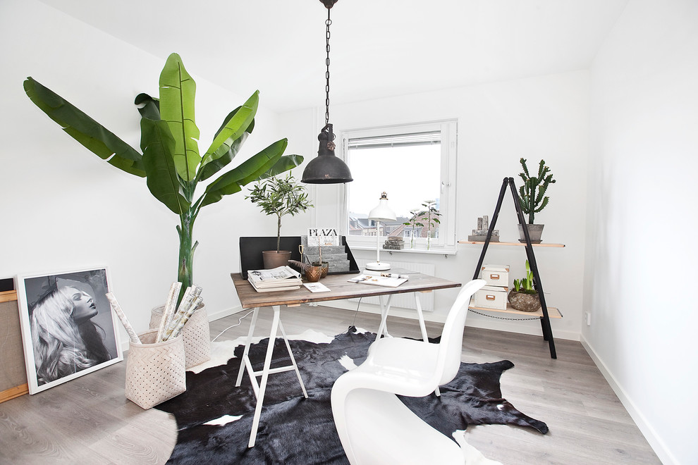 Nordisk inredning av ett mellanstort hemmastudio, med vita väggar, ljust trägolv och ett fristående skrivbord