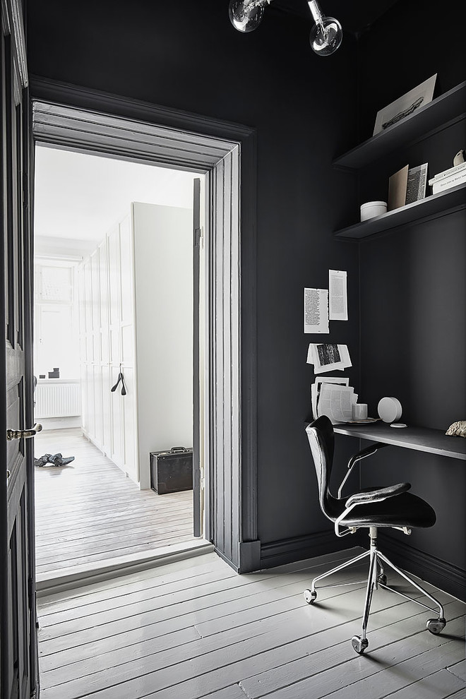 Ejemplo de despacho escandinavo de tamaño medio sin chimenea con paredes negras, suelo de madera pintada y escritorio independiente