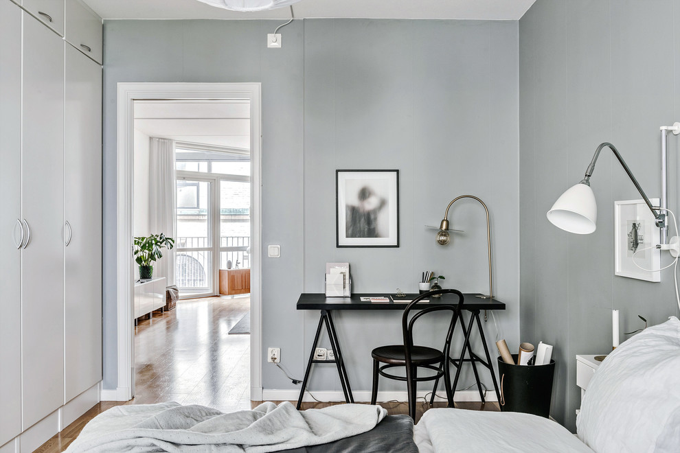 Inspiration för små minimalistiska arbetsrum, med grå väggar, mellanmörkt trägolv och ett fristående skrivbord