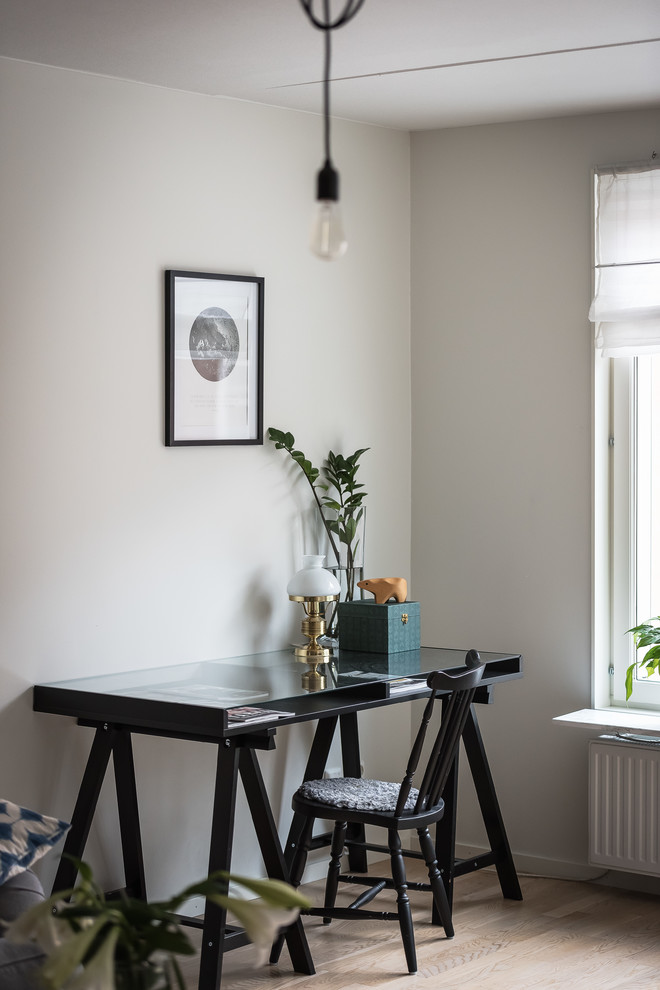 Design ideas for a scandinavian home office in Orebro with light hardwood flooring, a freestanding desk, beige floors and grey walls.