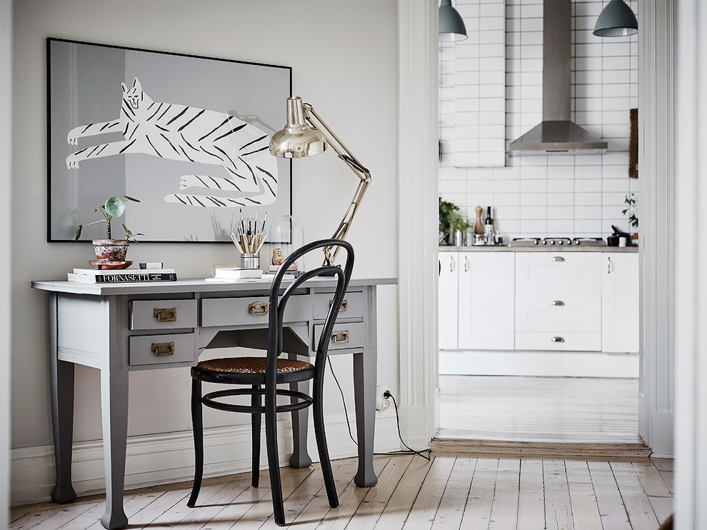 Nordisk inredning av ett arbetsrum, med grå väggar, målat trägolv, ett fristående skrivbord och vitt golv