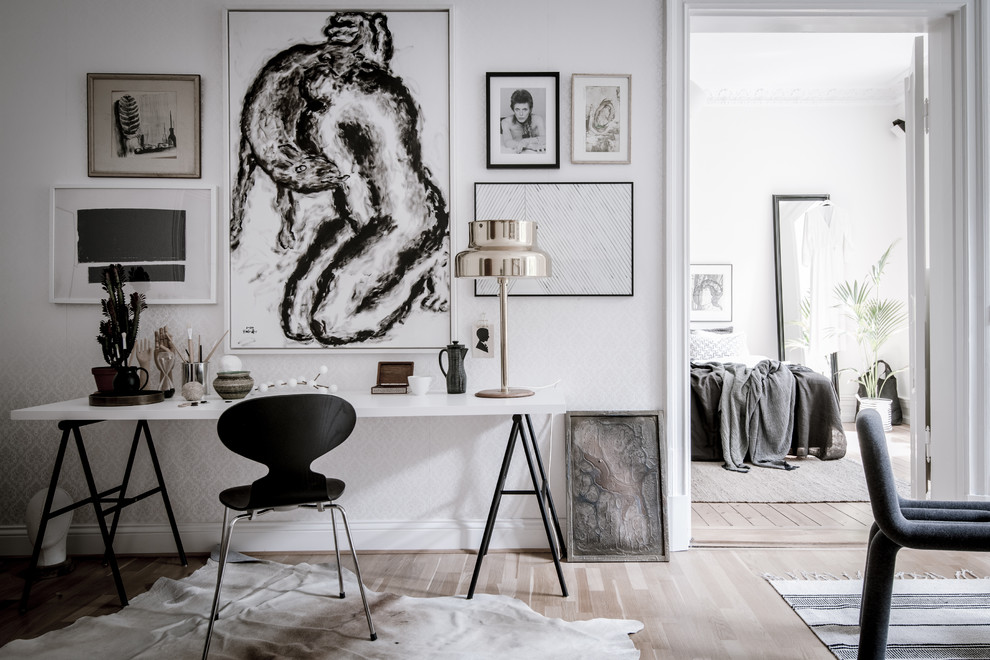 Ejemplo de sala de manualidades escandinava grande con paredes blancas, suelo de madera clara y escritorio independiente
