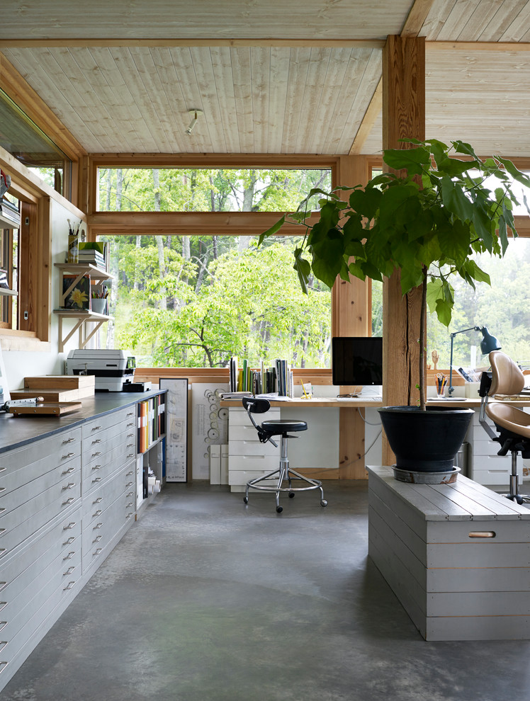 На фото: большой кабинет в восточном стиле с бетонным полом, отдельно стоящим рабочим столом и серым полом без камина