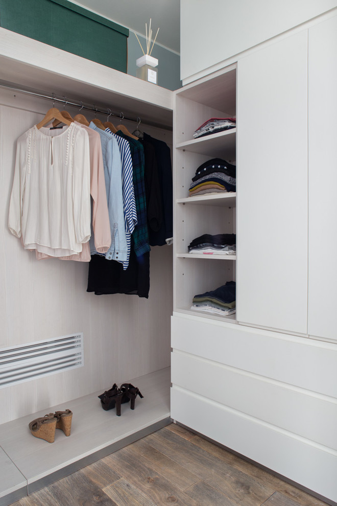 Bild på en mellanstor funkis garderob för kvinnor, med släta luckor, vita skåp och mellanmörkt trägolv