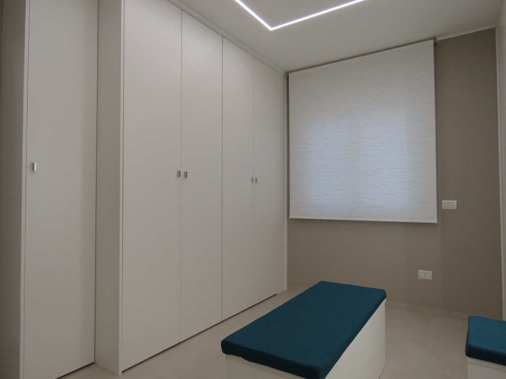 Cette photo montre un grand dressing room tendance neutre avec un placard à porte plane, des portes de placard blanches, un sol en carrelage de porcelaine et un sol beige.
