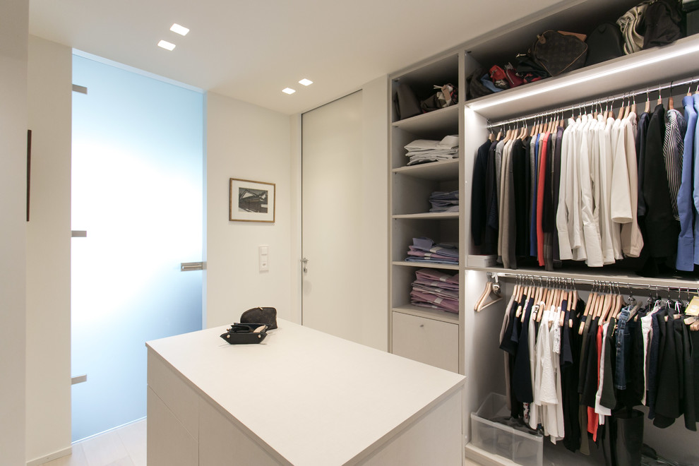 Photo of a large modern gender neutral dressing room in Milan with open cabinets.