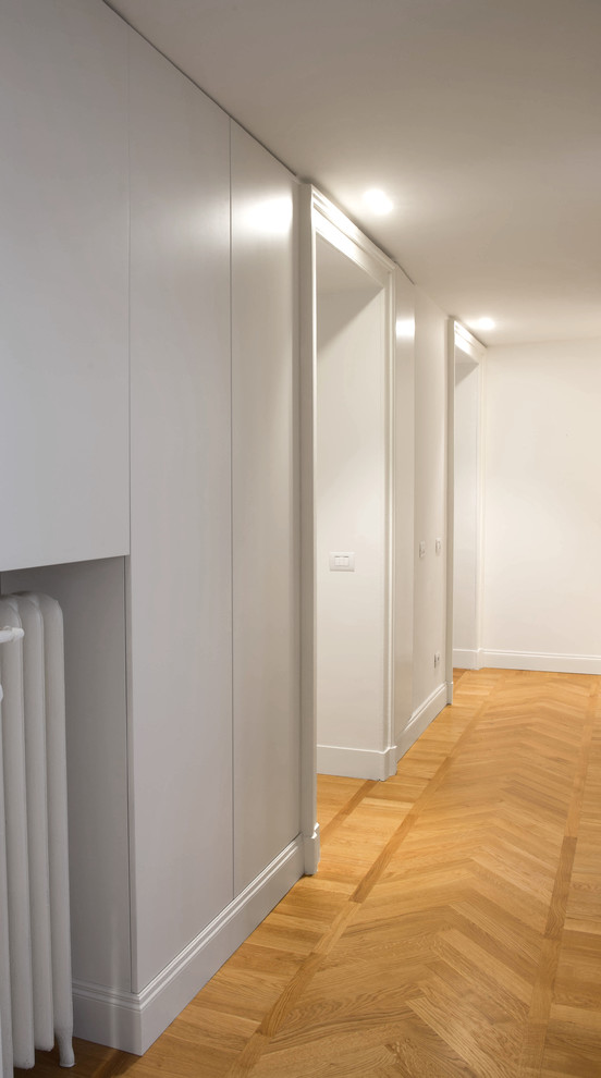Immagine di un piccolo armadio o armadio a muro unisex contemporaneo con ante lisce, ante bianche e pavimento in legno massello medio
