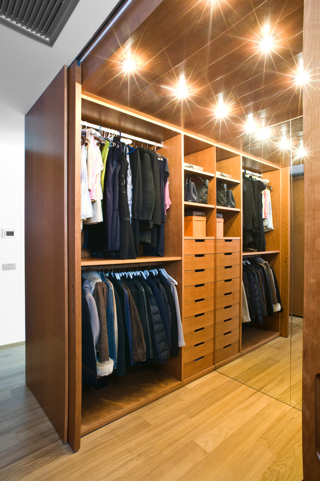 Imagen de armario vestidor unisex contemporáneo de tamaño medio con armarios abiertos, puertas de armario de madera oscura y suelo de madera clara