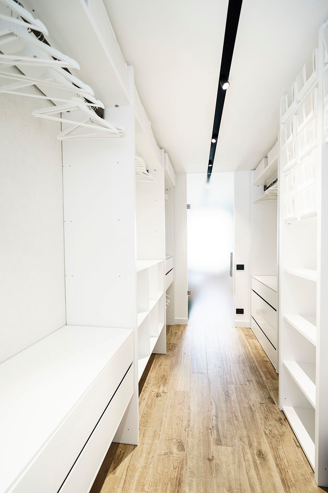 Foto di un grande spazio per vestirsi unisex minimalista con nessun'anta, ante bianche e pavimento in legno massello medio