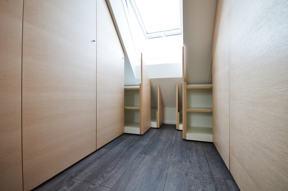 Ejemplo de armario unisex actual de tamaño medio con armarios con paneles lisos, puertas de armario de madera clara, suelo de madera oscura y suelo gris