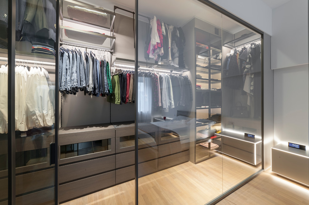 Foto de armario vestidor unisex actual de tamaño medio con armarios con paneles lisos, puertas de armario marrones, suelo de madera clara y suelo beige
