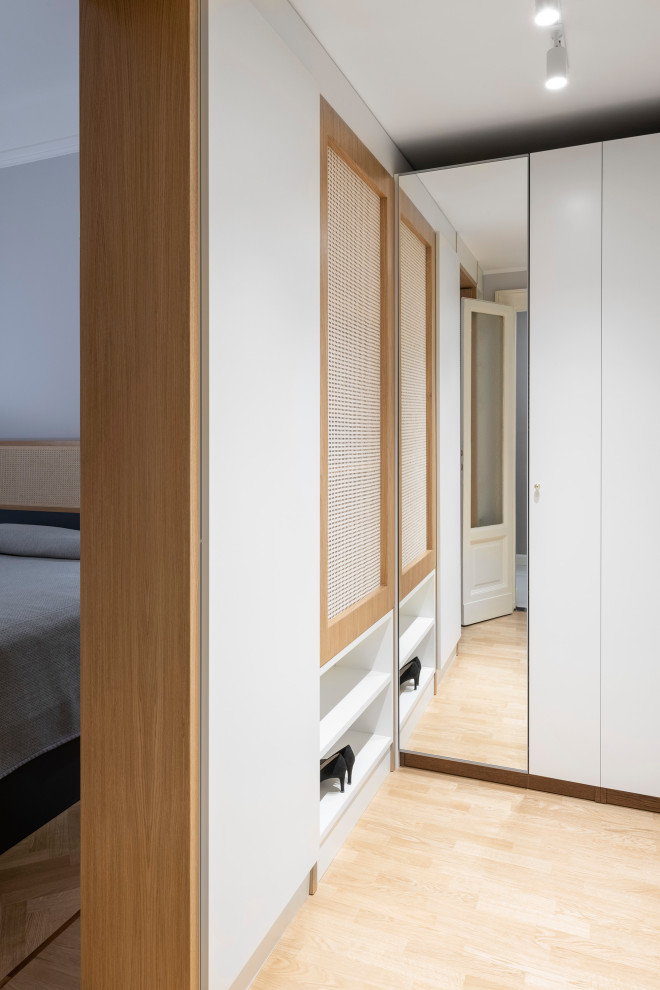 Imagen de armario vestidor unisex escandinavo de tamaño medio con armarios con paneles lisos, puertas de armario blancas, suelo de madera clara y bandeja