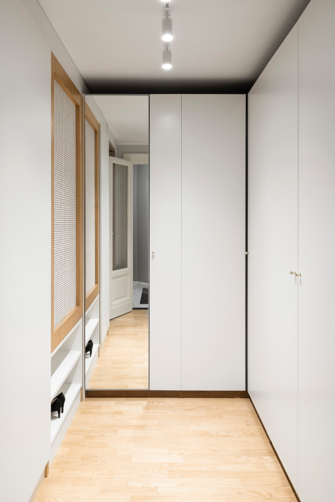 Cette photo montre un dressing scandinave de taille moyenne et neutre avec un placard à porte plane, des portes de placard blanches, parquet clair et un plafond décaissé.