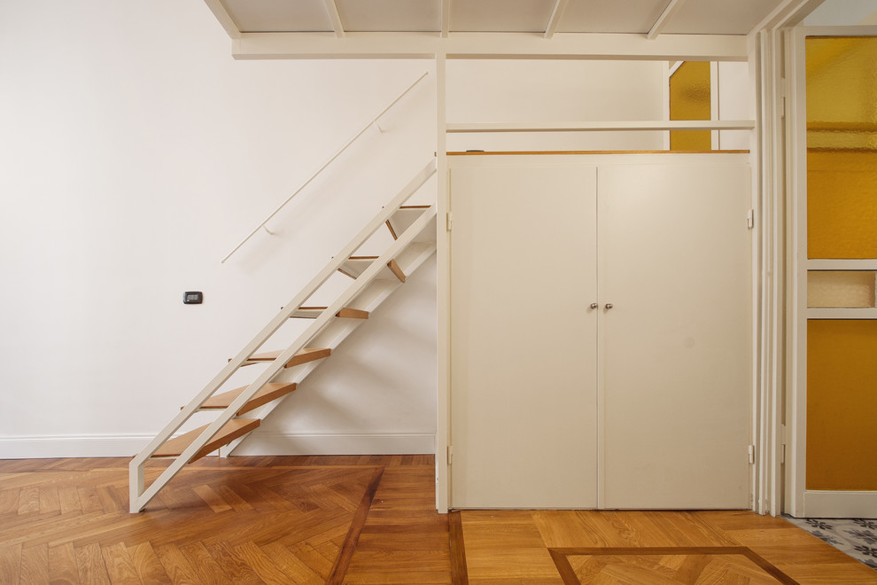 Imagen de armario unisex industrial pequeño con armarios con paneles lisos, puertas de armario blancas, suelo de madera en tonos medios y suelo marrón