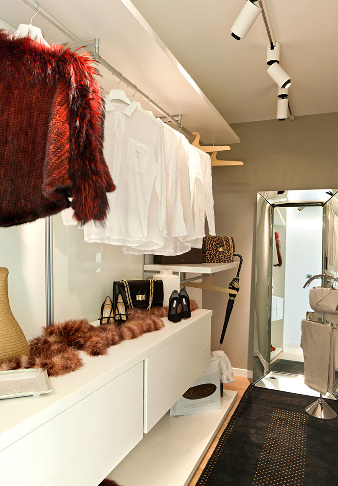 Aménagement d'un dressing room contemporain de taille moyenne pour une femme avec un placard sans porte et des portes de placard blanches.