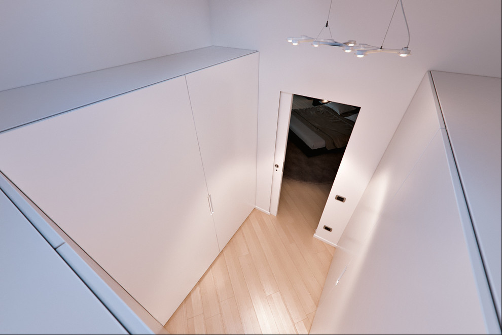 Foto di una piccola cabina armadio unisex design con ante lisce, ante bianche e parquet chiaro