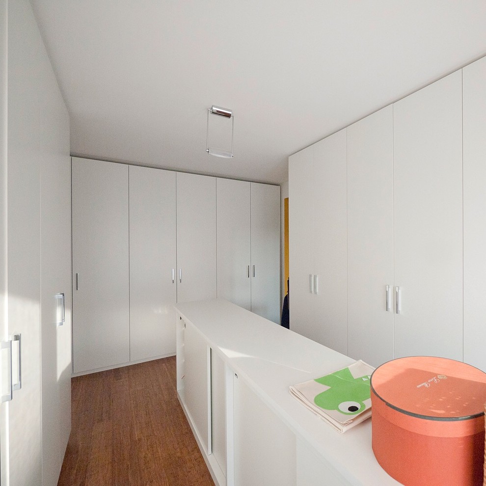 Immagine di un grande armadio o armadio a muro unisex minimalista con ante lisce, ante bianche e pavimento in bambù