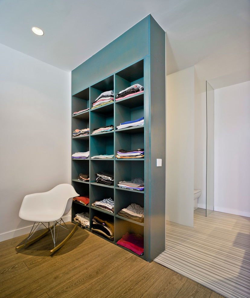 Foto de vestidor unisex actual de tamaño medio con armarios abiertos, puertas de armario azules y suelo de madera en tonos medios