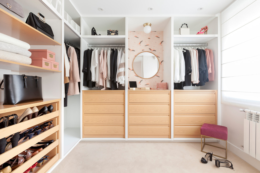 Contemporary walk-in wardrobe for women with light wood cabinets, carpet, beige floors and a feature wall.