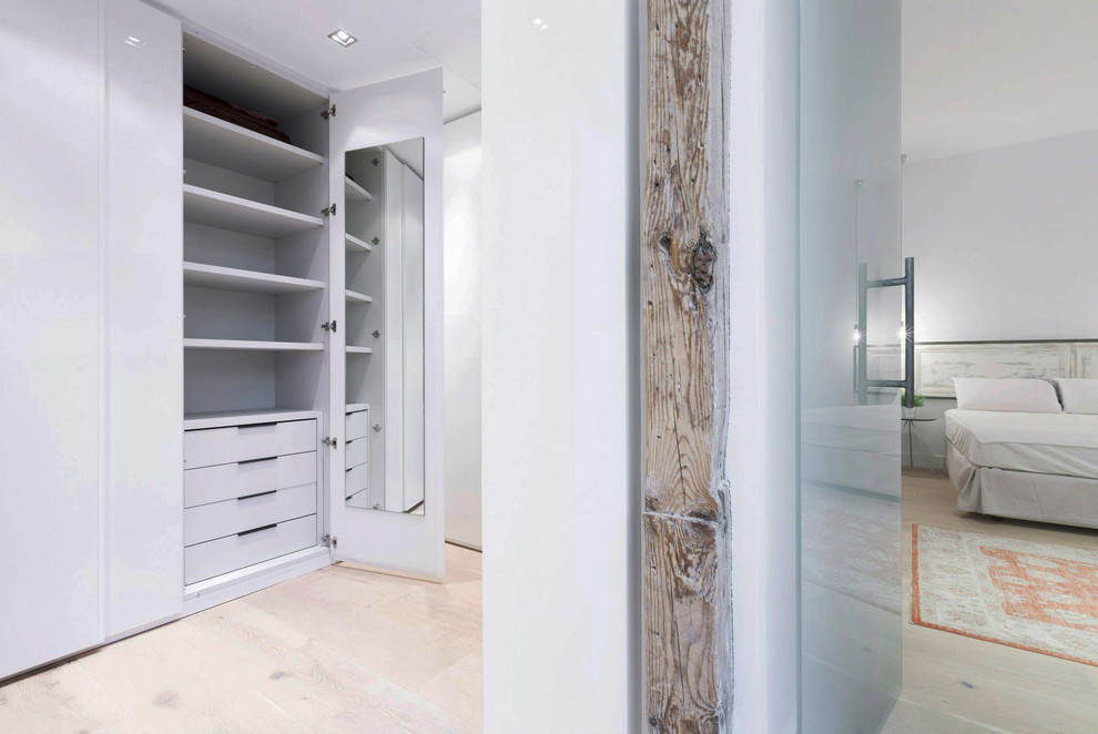 Foto de armario vestidor unisex tradicional renovado de tamaño medio con armarios con paneles lisos, puertas de armario blancas y suelo de madera clara