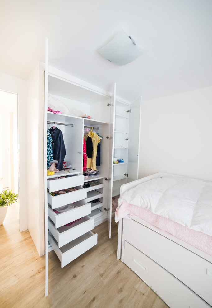 Diseño de armario de mujer contemporáneo de tamaño medio con armarios con paneles lisos, puertas de armario blancas y suelo de madera clara