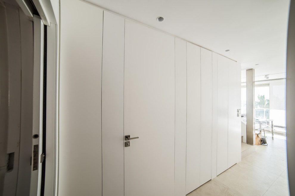 Ejemplo de armario unisex actual de tamaño medio con armarios con paneles lisos y puertas de armario blancas