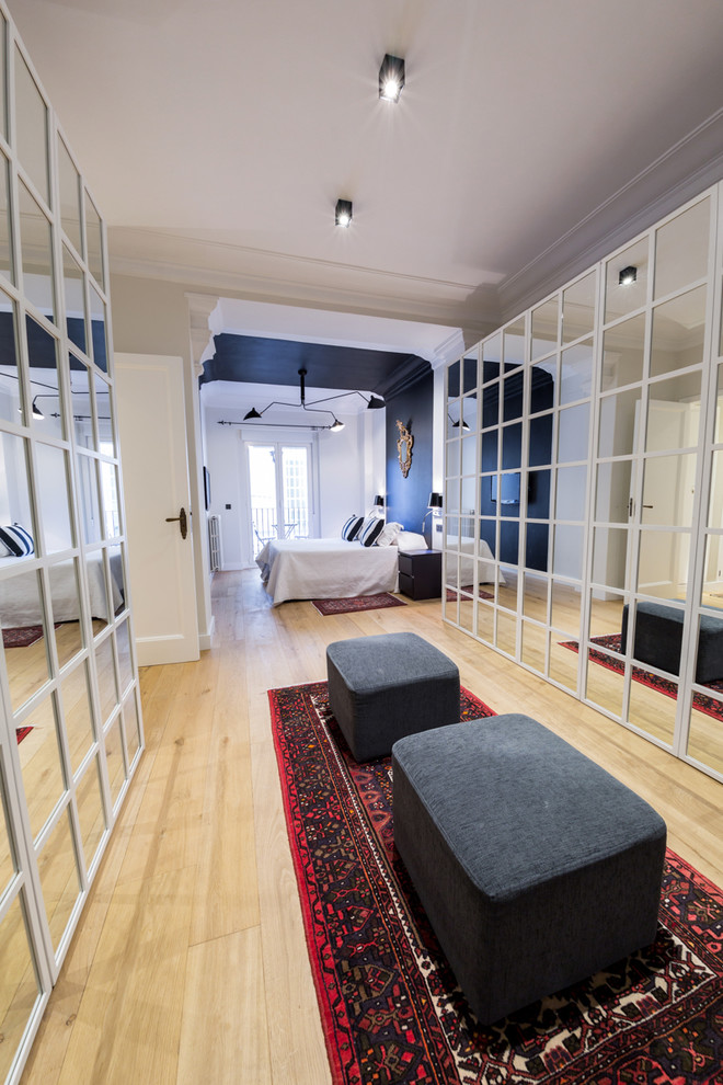 Foto di uno spazio per vestirsi unisex design di medie dimensioni con ante di vetro, ante bianche e pavimento in legno massello medio
