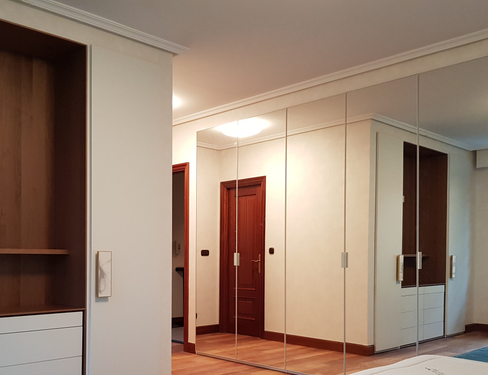 Ejemplo de armario y vestidor unisex actual de tamaño medio con a medida y suelo de madera en tonos medios